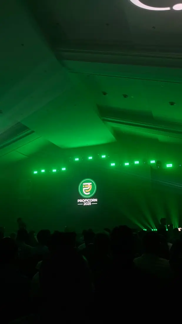 The Proficorn 2025 logo on stage in a hall lit green